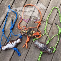 four necklaces with different designs on them sitting on a wooden floor, one is orange and the other is blue