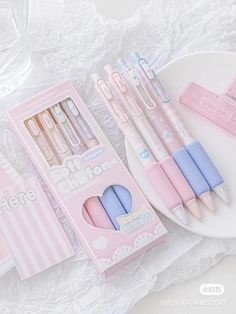 three pink and blue pens sitting on top of a white plate next to two boxes