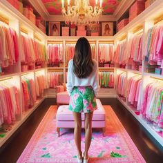 a woman standing in front of a closet filled with pink and green clothes on hangers