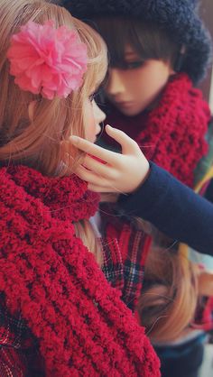 two dolls are dressed up and one is wearing a red scarf