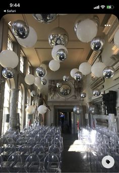 a room filled with lots of clear chairs and shiny balls hanging from the ceiling above them