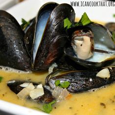 a bowl filled with mussels and garnishes in broth sauce