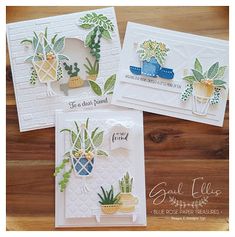 three cards with plants on them sitting on top of a wooden table next to each other