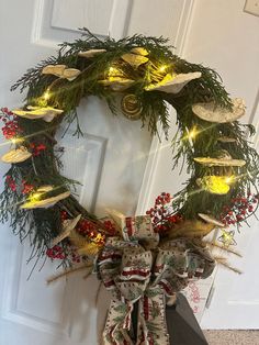 a christmas wreath with lights on it sitting in front of a door that is decorated