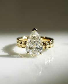 a pear shaped diamond engagement ring set in yellow gold