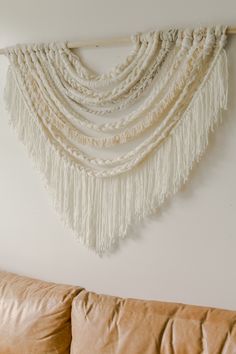 a white wall hanging with tassels on it's side in a living room