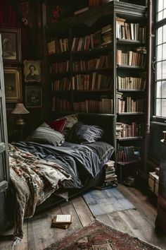 a bed sitting in front of a book shelf filled with books next to a window