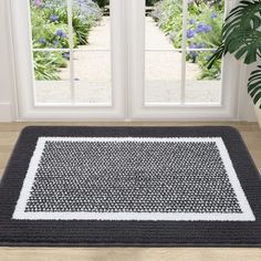 a black and white area rug in front of a window with potted plants next to it