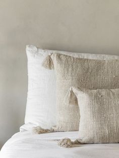 two pillows with tassels sit on a bed