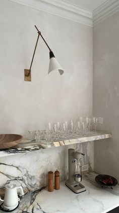 a kitchen with marble counter tops and white walls, an overhead light hangs over the sink