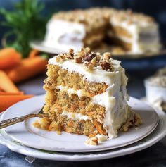 a piece of carrot cake on a plate with a fork in front of the slice