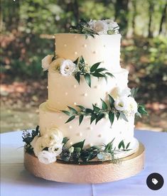 a wedding cake with white flowers and greenery