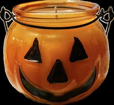 an orange pumpkin shaped candle holder with black eyes