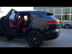 a black car with red seats is parked in front of a building and has its door open