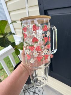 someone holding up a glass with strawberries and daisies on it