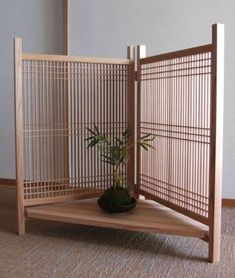 a small potted plant sitting in front of a wooden screen on top of a floor