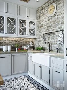 a kitchen with white cabinets and a black and white rug in front of the sink