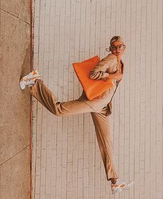 a woman is standing on one leg and holding an orange bag