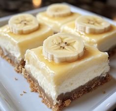 four slices of cheesecake with banana slices on top, sitting on a white plate