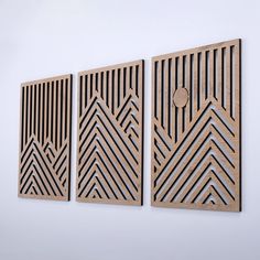 three pieces of wood with geometric designs on the wall above them, one has a circular hole in the middle