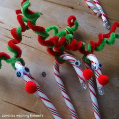 three candy canes decorated with red, green and white christmas decorations on a wooden surface