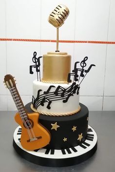 a three tiered cake with musical instruments and music notes on the top, as well as a guitar