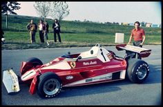 a man standing next to a red race car