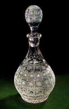 a glass decanter sitting on top of a green cloth covered table next to a black background