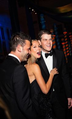 two men and a woman in tuxedos standing next to each other at an event