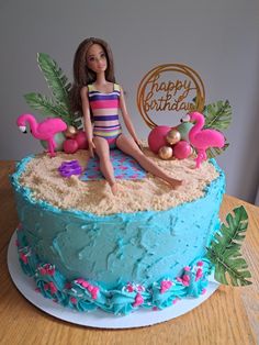 a birthday cake with a barbie doll sitting on top of it and flamingos around the edges