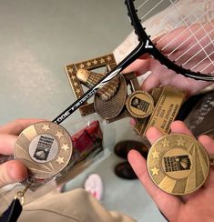 a person holding two tennis racquets and several medals in their hands,