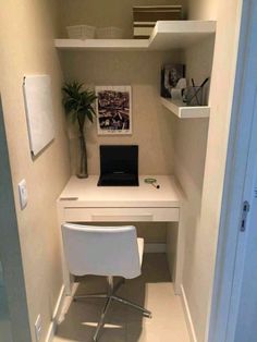 a white desk with a laptop on it in a small room next to a door