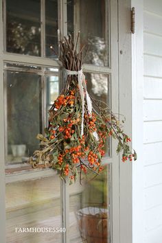 a wreath hanging from the side of a door with berries and leaves on it's hanger