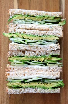 four sandwiches are stacked on top of each other, with cucumbers and cream cheese