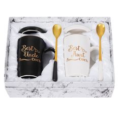 two black and white coffee mugs in a gift box with gold spoons on the side