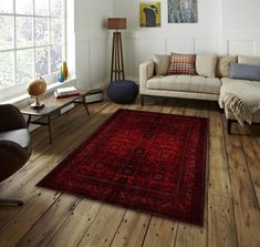 a living room filled with furniture and a red rug on top of a hard wood floor