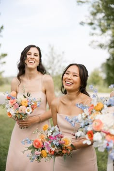 two bridesmaids laughing and holding bouquets in their hands