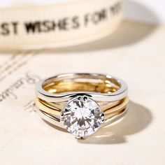 two gold and silver wedding rings with a single diamond in the center, on top of a piece of paper