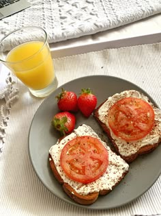 two pieces of bread with tomatoes and cheese on them next to a glass of orange juice