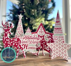 three wooden christmas trees on top of a table next to a christmas tree and window