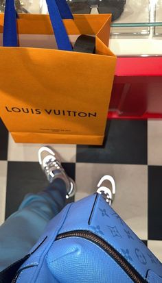 a blue louis vuitton bag sitting on top of a black and white checkered floor