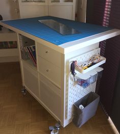 a blue and white workbench on wheels in a room with hard wood flooring