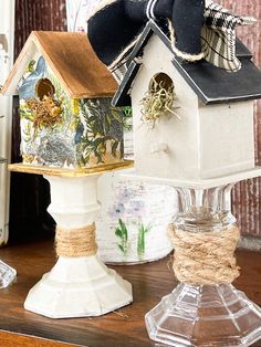 a birdhouse is sitting on a table next to some glass vases and other items