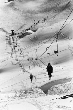 people are skiing down a snowy mountain with ski lifts in the background and snow on the ground