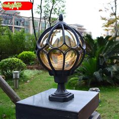 an old fashioned lamp sitting on top of a wooden box in the grass near some trees