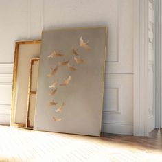 two framed pictures sitting on top of a hard wood floor next to a white wall