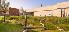 a building that is next to a grassy field with people walking in it and on the other side