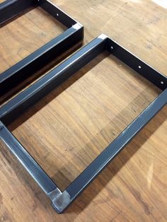 two metal frames sitting on top of a wooden table next to each other and one is missing