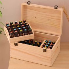 an open wooden box filled with bottles of essential oils sitting on a table next to a potted plant