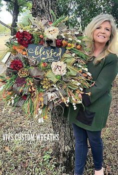 a woman standing next to a tree holding a sign that says, elli's custom wreaths